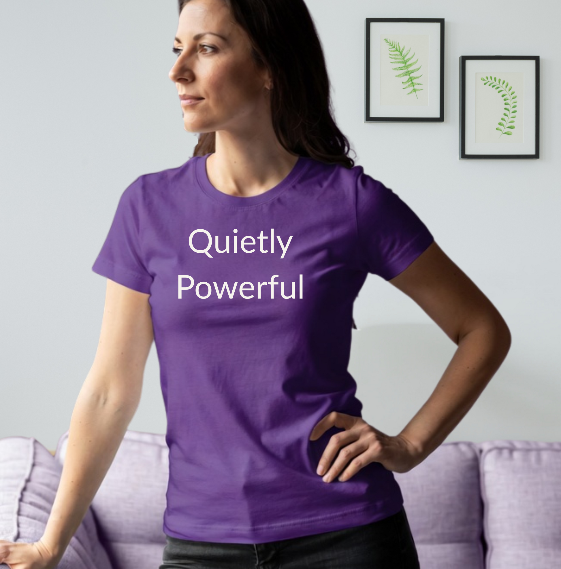 Woman wearing a purple t-shirt with 'Quietly Powerful' text in a living room setting.